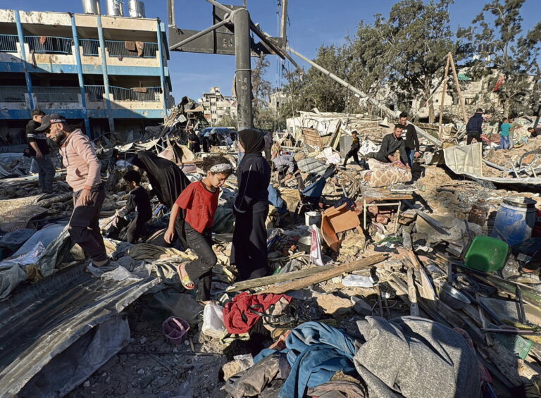 Palestinians inspect the damage caused by an Israeli airstrike targeting a school housing displaced people for the second time in Al-Bureij